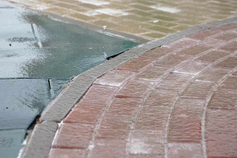 Pavement featuring a blend of brick and stone surfaces with a slightly wet, glistening finish